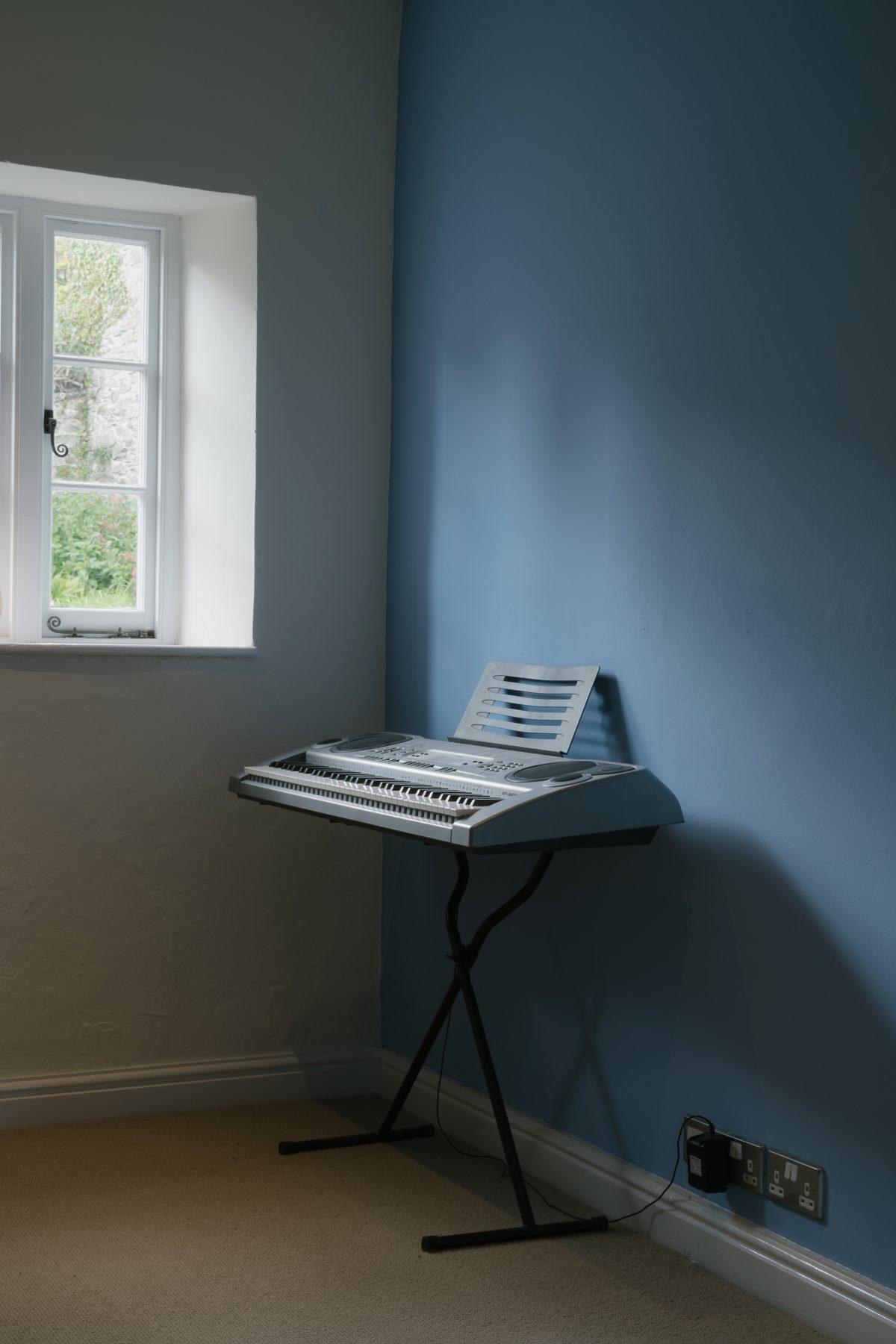 A keyboard in a the corner of a room with blue painted walls. Cornwall.