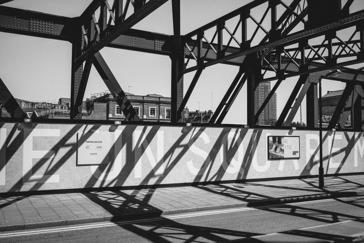 A bridge with some metal construction casting strong shadows onto the road.