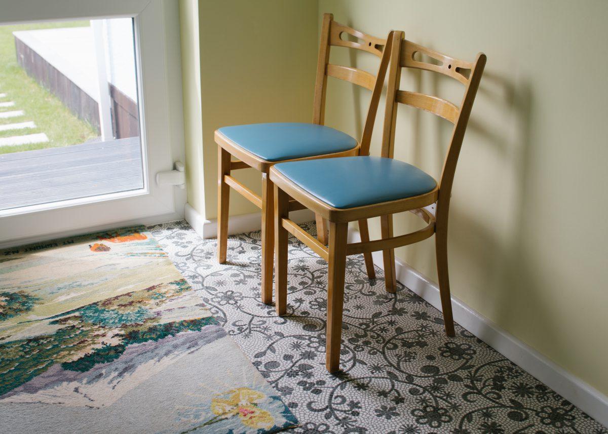 Two chairs by the back door in a utility room with rug. The rug shows a view of a mountain range.