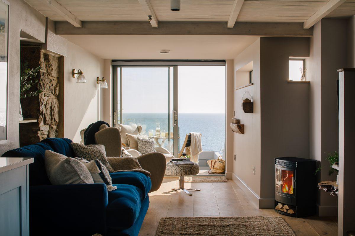 Lounge interior with wood burning stove and views out to sea. Located in Cornwall.