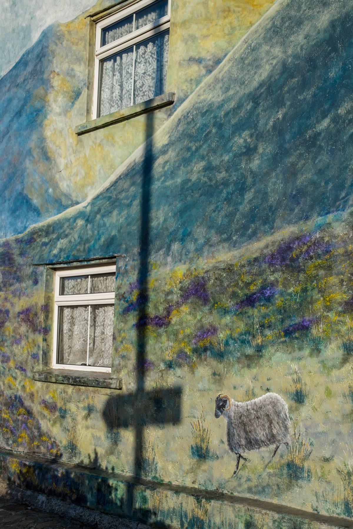 A mural showing sheep and countryside view on the side of a building in Okehampton, Devon.