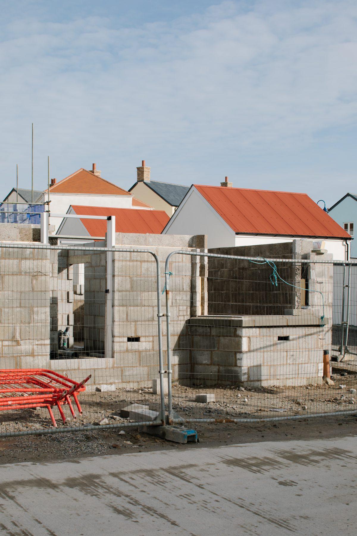 An image of a fenced in building site with completed houses beyond. Nansledan, Newquay.