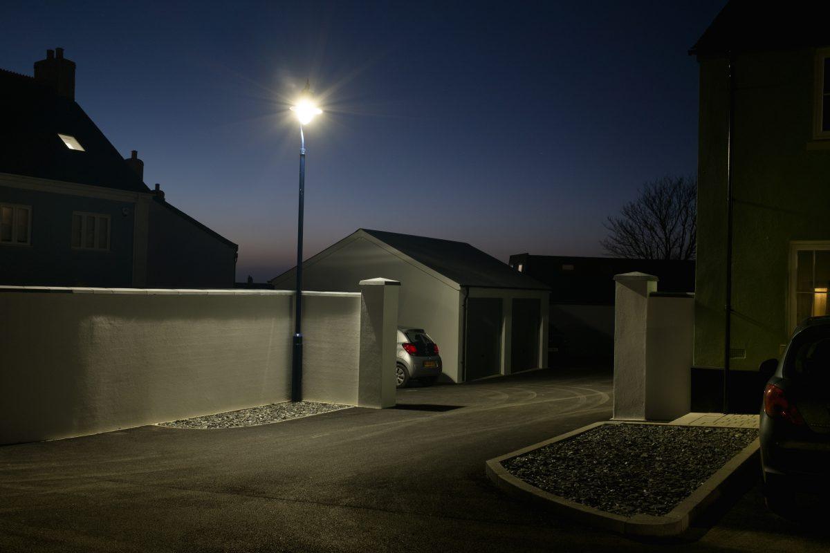 Shot at dusk. A view of a car in a driveway next to garages in Nansledan, Cornwall.