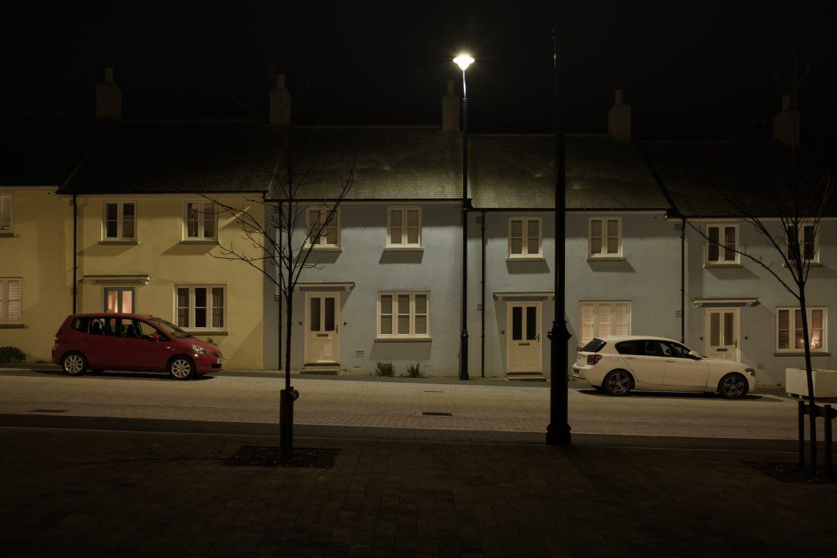 Night time image of Nansledan street showing cars parked in front of a row of terraced houses. Newquay, Cornwall.