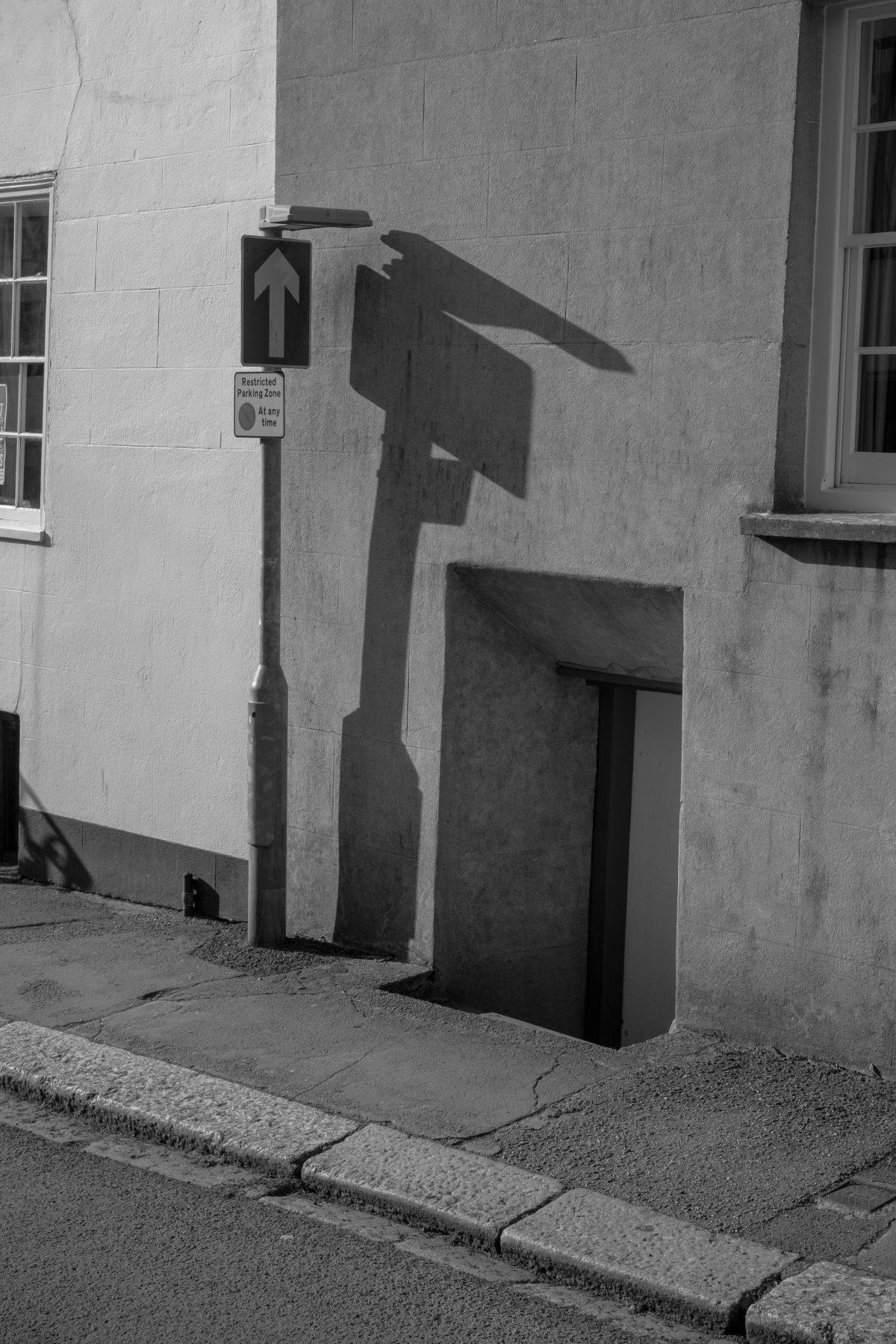 Detailed photograph of a street sign in Fowey. With strong evening light casting shadow.