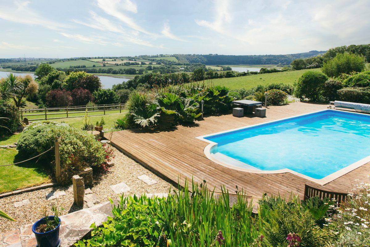 Swimming pool in garden with views towards Carrick Roads. Photographed on location in Cornwall.