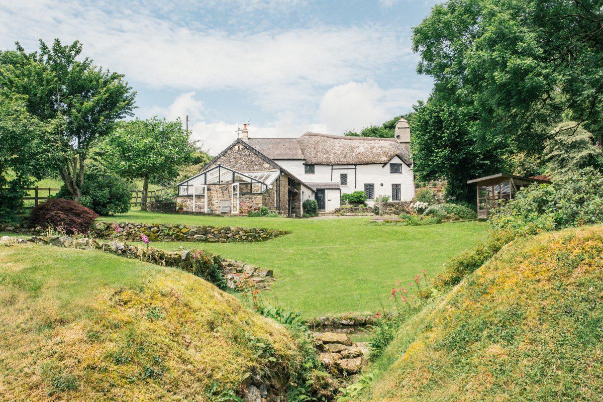 Thatched cottage with large garden in the foreground.